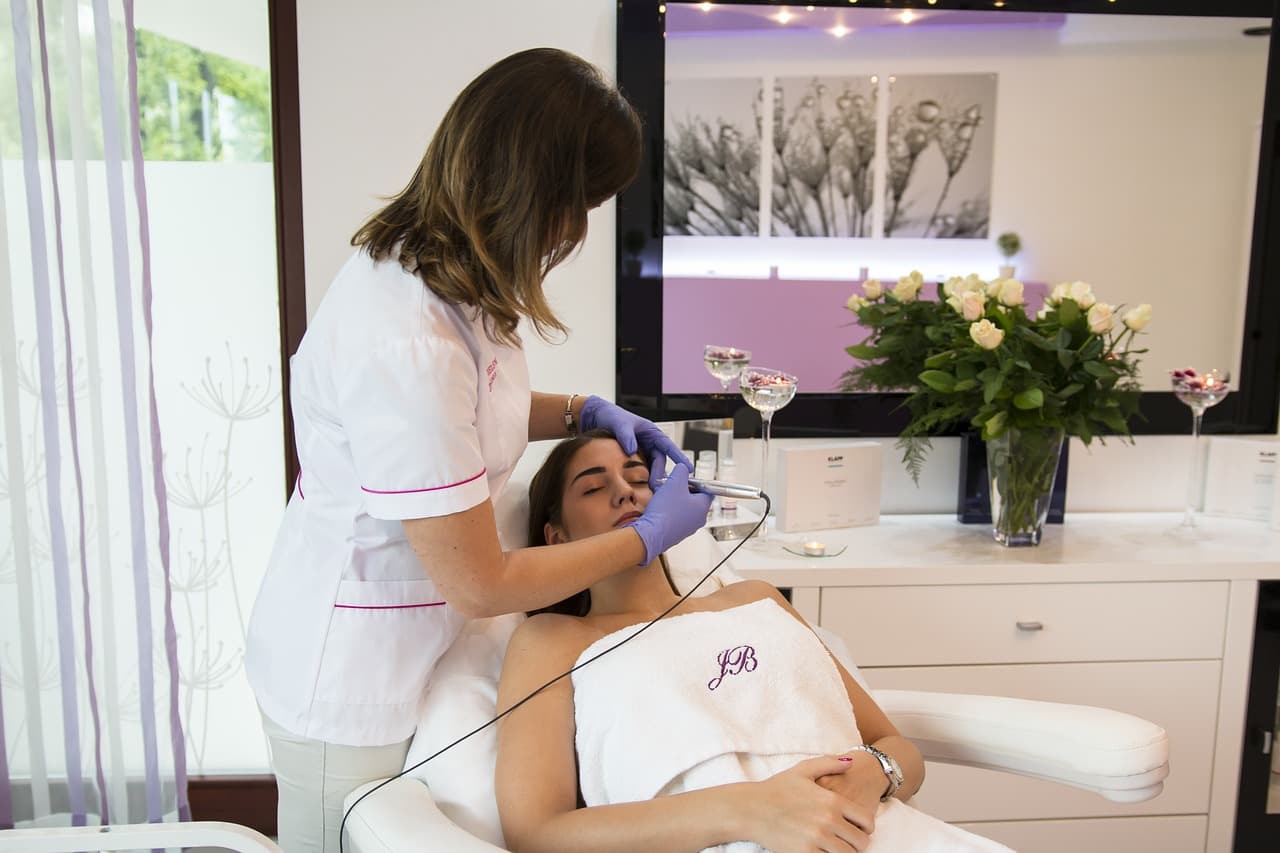 Practitioner giving a facial treatment in a clinic room